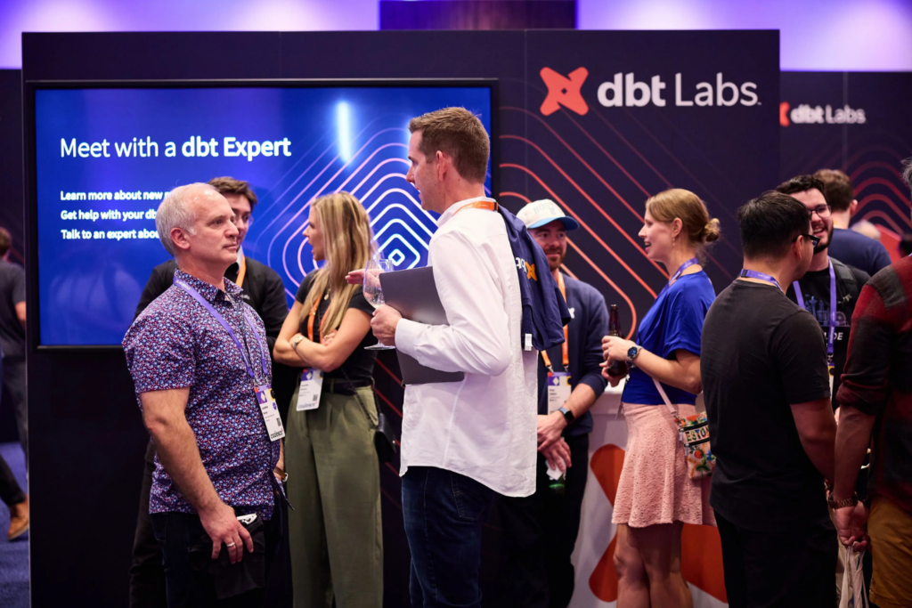 Professionals networking and speaking with experts at dbt Summit exhibition area